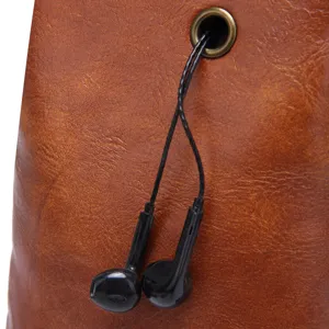 Close-up detail showing the functional earphone port on a vintage brown leather bag.