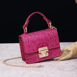 Primer plano de detalle de bolso magenta con patrón de cocodrilo y cierre dorado