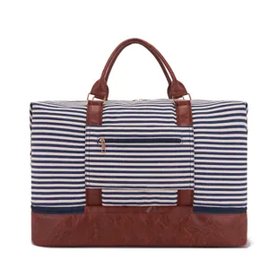 Bolsa de viaje grande en lona a rayas con adornos de cuero marrón y bolsillo exterior.