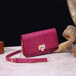 Bolso bandolera fucsia con grabado de cocodrilo, cierre dorado y correa de cadena