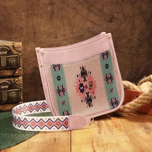 Detalle de bolso bandolera bohemio con un motivo occidental y un ribete rosa