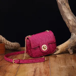 Primer plano de un bolso fucsia vintage con textura de cocodrilo y detalles dorados.
