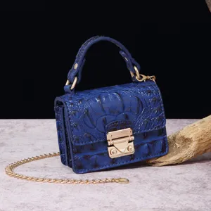 Detalle de bolso vintage azul con textura de cocodrilo y cierre dorado elegante