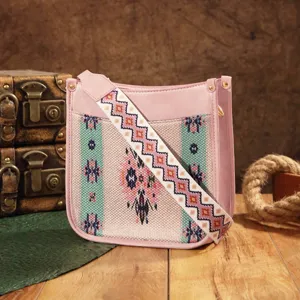 Bolso bandolera bohemio rosa vintage con correa étnica sobre fondo de madera rústica