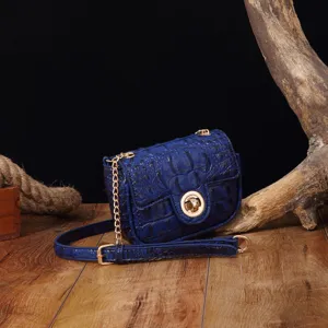 Detalle de bolso bandolera vintage azul con relieve de cocodrilo y herrajes dorados