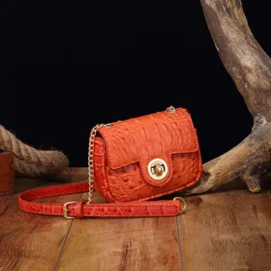 Primer plano de un bolso vintage naranja con grabado de cocodrilo sobre fondo de madera rústica