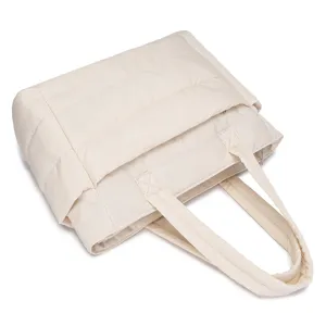 Detail view of a lightweight quilted beige puffer tote bag for travel and gym use.