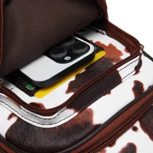 Detailed close-up view of cow print crossbody bag interior showing phone and card slots