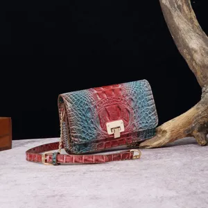 Detalle de bolso bandolera vintage de cuero con diseño de cocodrilo rojo y azul