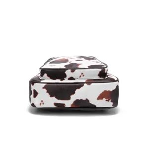 Bottom view of a small Western-style chest bag with brown cow print on white leather.