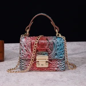 Detalle de bolso vintage con motivo de cocodrilo, degradado rojo azul y herrajes dorados.