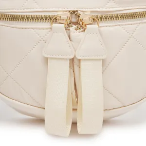 Primer plano de las cremalleras dobles doradas y patrón acolchado en bolso beige