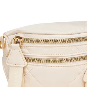 Detalle de cremalleras doradas y patrón acolchado en bolso bandolera Oxford crema