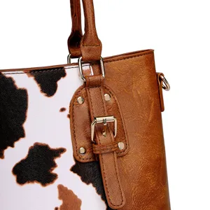 Primer plano de un bolso vintage con estampado de vaca y cuero marrón con hebilla dorada.
