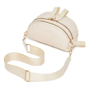 Vista detallata del bolso bandolera de nailon acolchado crema con doble cremallera.