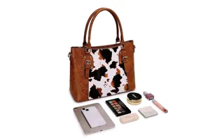 Bolso vintage con estampado de vaca mostrado con una tableta y cosméticos varios.
