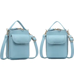 Detalle del bolso bandolera azul claro para móvil con correa ajustable y herrajes dorados.