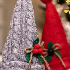 Detaillierte Nahaufnahme von gestrickten Weihnachtswichteln mit Stechpalmen-Dekor