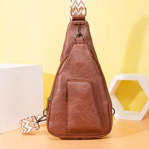 Detalle de un bolso bandolera de cuero PU marrón con una elegante correa ancha estampada.