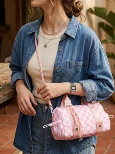 Modello che indossa una borsa a cilindro a scacchi rosa e bianca come accessorio da viaggio.