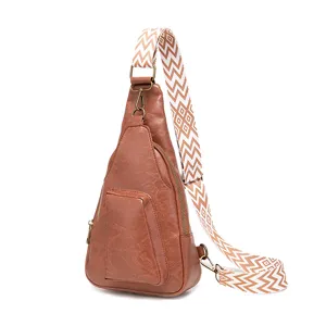 Detalle de bolso bandolera vintage de cuero marrón con una correa ancha de tela estampada