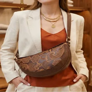 Modelo con bolso de media luna marrón vintage grabado, top color óxido y chaqueta beige