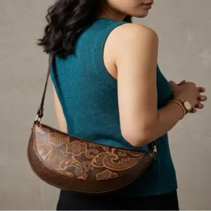 Elegante bolso de hombro floral vintage en forma de luna sobre modelo en top verde.