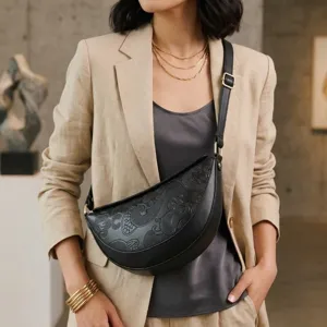 Modelo luciendo un bolso de pecho negro con relieve vintage y correa ajustable