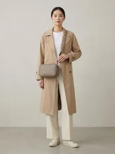 Modelo asiática luciendo un bolso bandolera tipo cámara en color topo con doble cremallera
