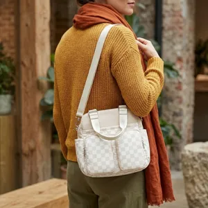 Primer plano de un bolso bandolera beige de cuadros con múltiples bolsillos en modelo