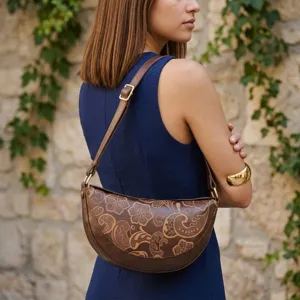 Bolso bandolera de media luna vintage grabado mostrado en modelo sobre fondo de pared