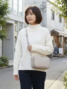 Elegante bolso bandolera de cuero gris claro llevado por una mujer en entorno urbano