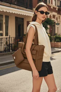 Lifestyle-detail van een bruine gewatteerde tote bag gedragen door een model in de stad