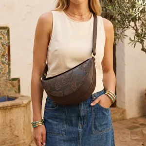 Bolso bandolera marrón con relieve vintage llevado por una modelo en un patio