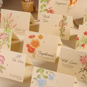 Primer plano de tarjetas de felicitación vintage de kraft con flores y textos en inglés.