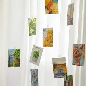 Tarjetas de felicitación florales colgadas en una cortina blanca en un entorno acogedor.