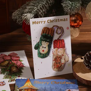 Detalle de tarjeta de Navidad con guantes de pan de oro y decoraciones festivas cálidas