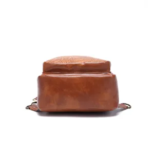 Bottom detail of a vintage brown bohemian sling bag featuring embossed floral patterns