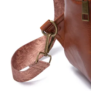 Close-up of vintage bronze hardware and embossed paisley strap on brown sling bag