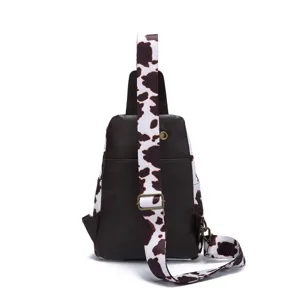Detail view of vintage western cow print sling bag with brown leather and wide strap