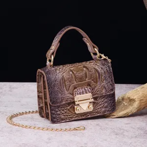Detalle de bolso vintage con textura de cocodrilo y una elegante cadena dorada.