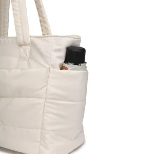 Detail shot of a white quilted travel bag showing a functional side pocket with an umbrella