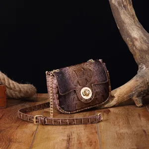 Detalle de bolso bandolera vintage de piel con relieve de cocodrilo y cadena de oro