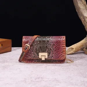 Vista de cerca de bolso bandolera vintage de cuero con relieve de cocodrilo y cierre dorado.