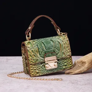 Detalle del bolso pequeño de lujo verde con grabado de cocodrilo y correa de cadena