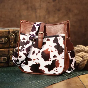 Detailed view of Western style cow print crossbody bag with vintage leather trim.
