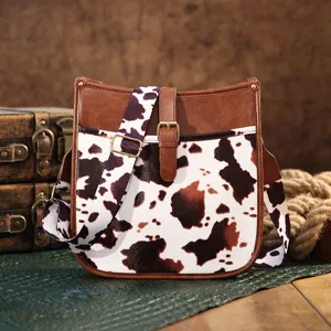 Detail view of a western-style cow print crossbody bag with vintage leather accents