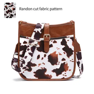 Detail view of the random cut cow print fabric pattern on a western crossbody bag.