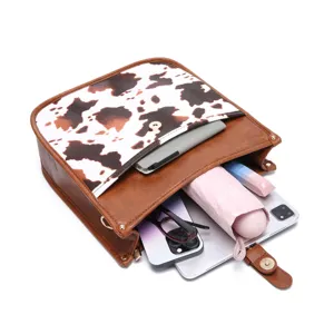 Internal view of cow print crossbody bag showing capacity for tablet, phone, and umbrella
