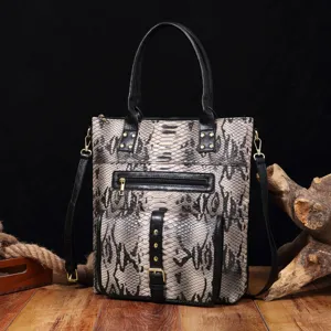 Close-up of a vintage snakeskin patterned tote bag resting on a rustic wood floor.